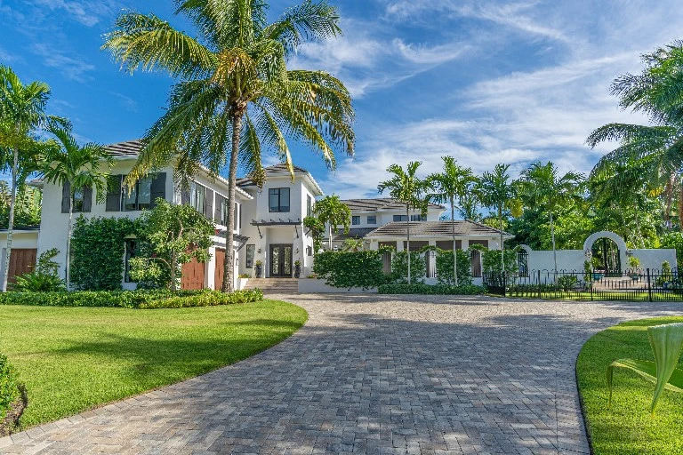 Old Naples luxury home exterior with circular paver driveway, gated entry, and tropical landscaping - luxury real estate in Old Naples Naples Florida